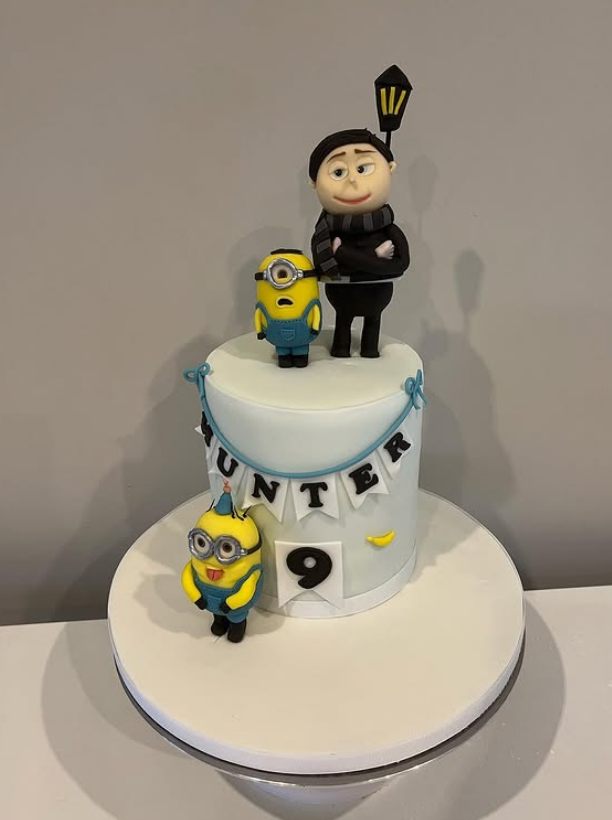 Two-tier character celebration cake on a white stand